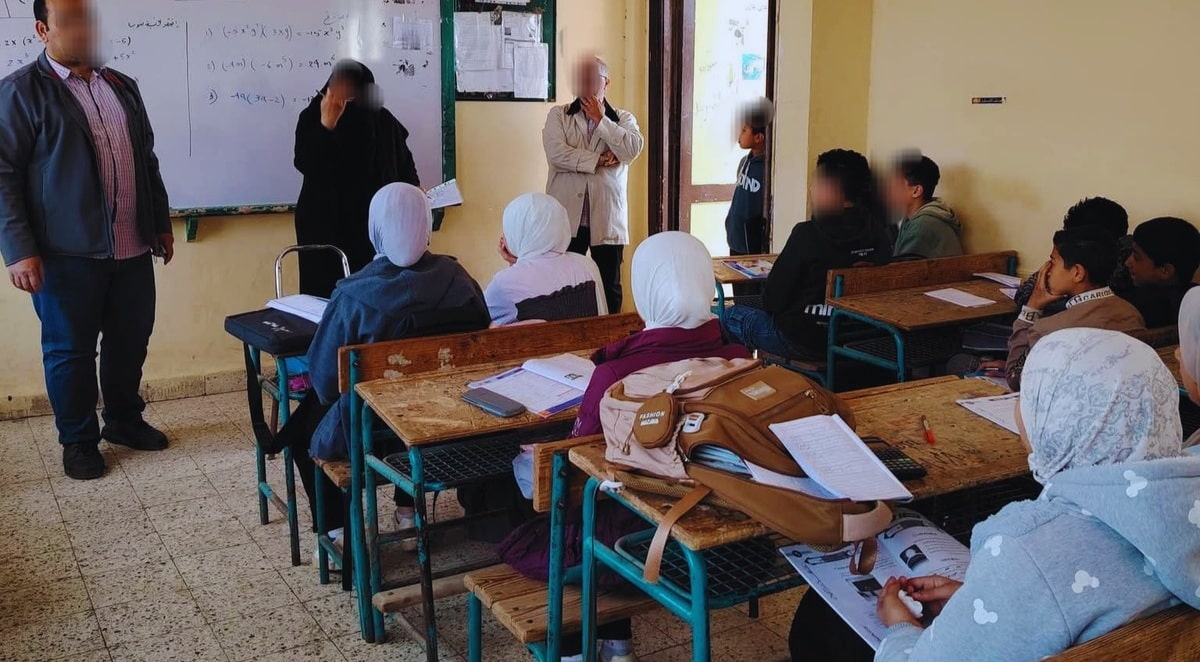 فصلًا دراسيًا في بيئة تعليمية، حيث يظهر معلمون يوجهون الطلاب خلال حصة دراسية